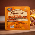 Lisanatti Almond Cheddar Style cheese package on a wooden surface with a grilled cheese sandwich in the background
